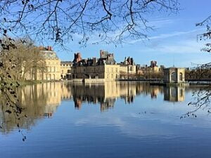 Château de Fontainebleau, se reflétant sur l'eau paisible de l'étang aux carpes.